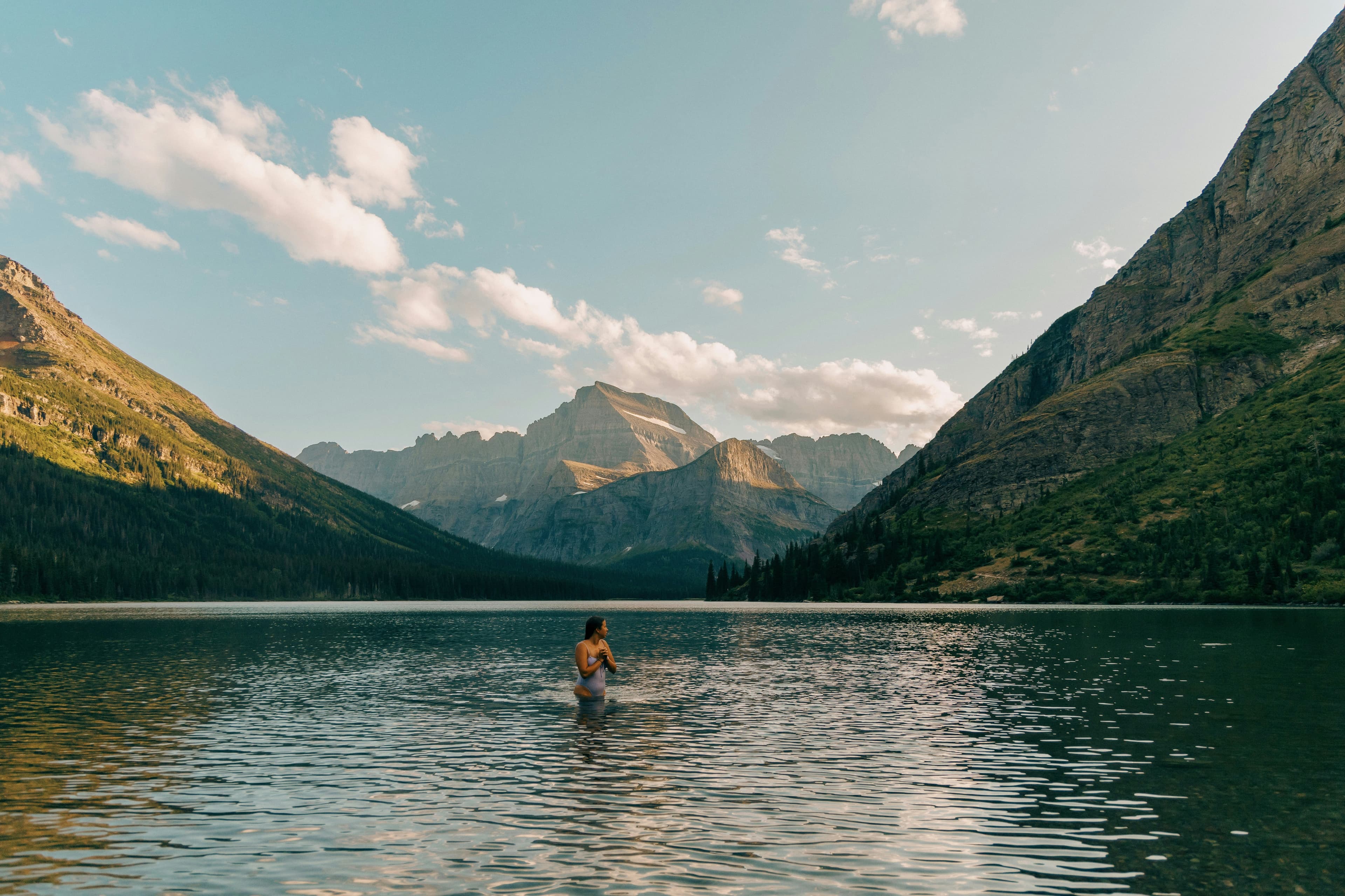 A woman swimming in a lake surrounded by mountains